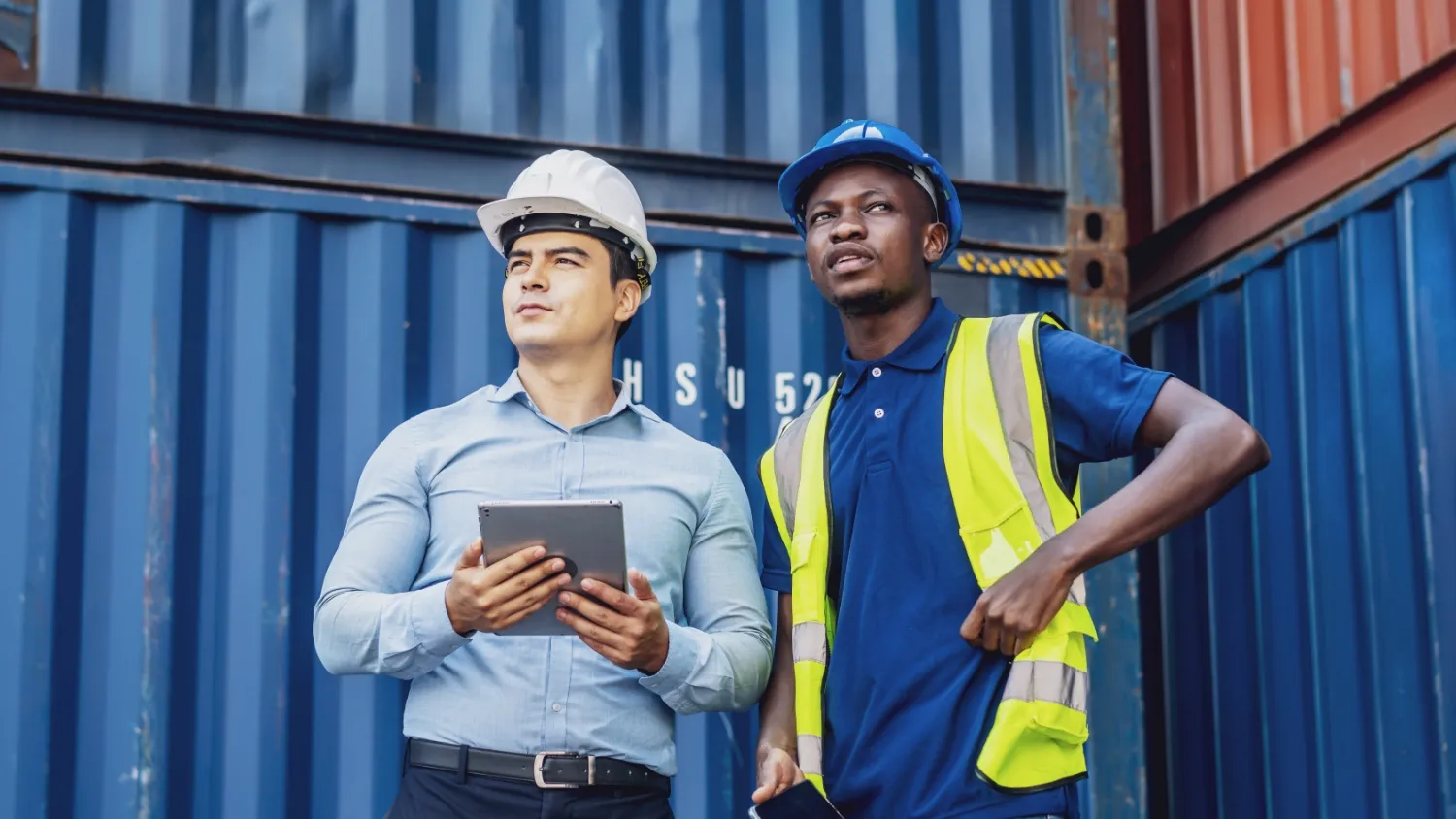 Dos hombres expertos en gestión portuaria frente a contenedores
