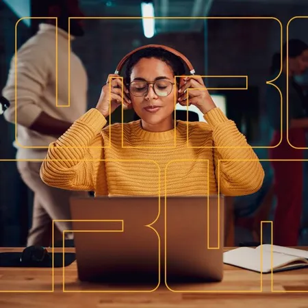 Mujer se coloca audífonos para tomar cursos virtuales UTB frente a su laptop